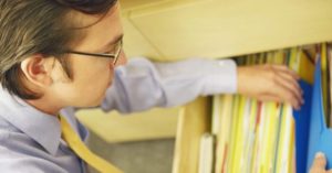A business man looking through a drawer full of files containing documents
