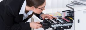 a professional woman looking inside an open office printer