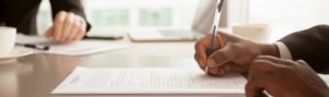 Man signing a contract at a desk
