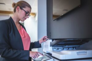 Businesswoman using an office printer, demonstrating the convenience and efficiency of Managed Print Services for document handling and printing tasks.