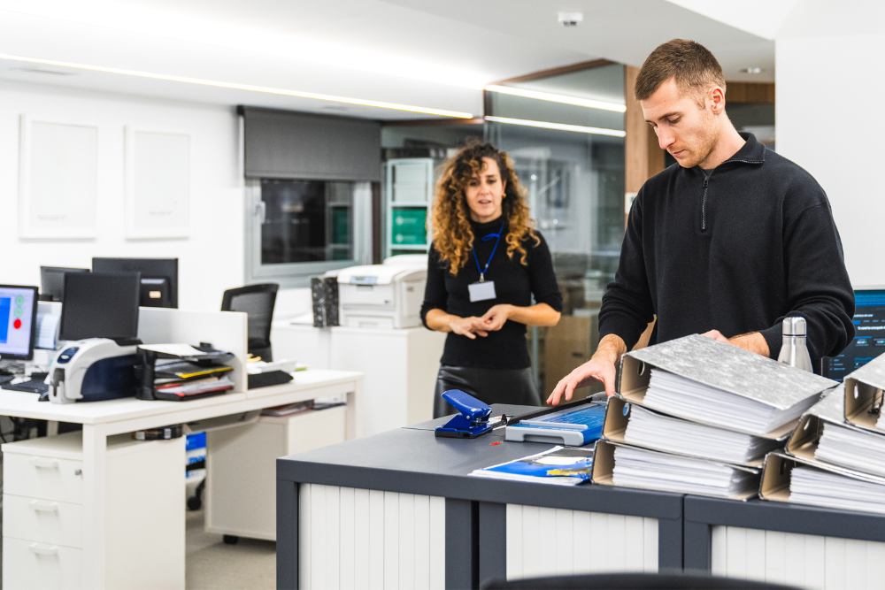 Two employees in an office copier room addressing papers to symbolize the importance of MPS.
